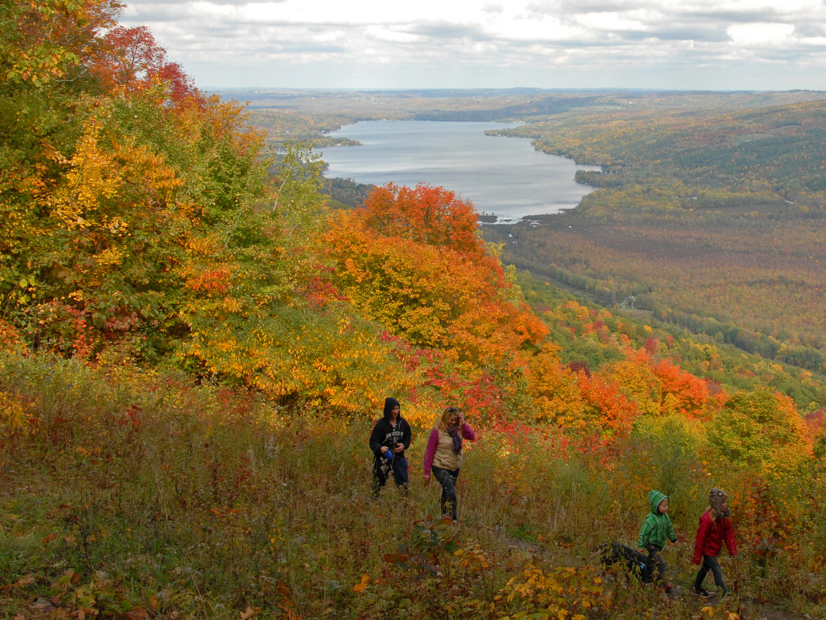 People walking along a trail high above a lake